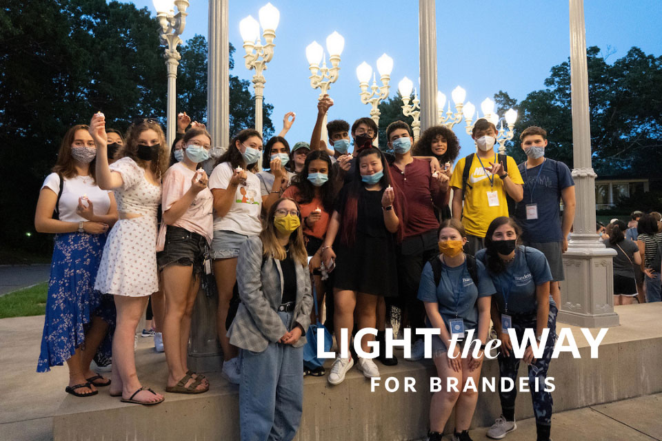students with masks standing in front of Light of Reason sculpture