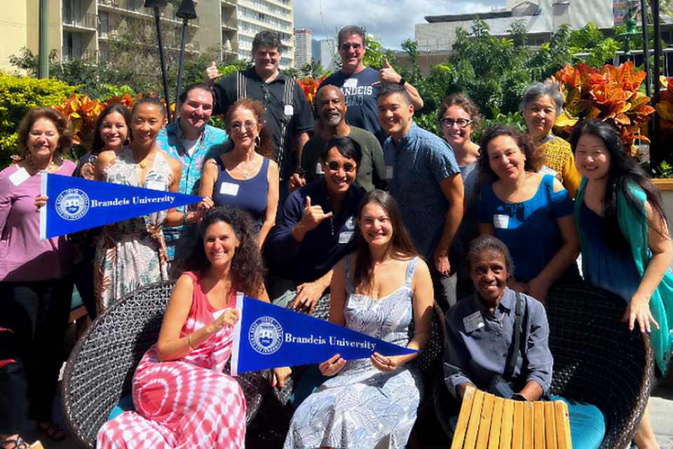 Group of alumni pose for the camera holding Brandeis pennants.