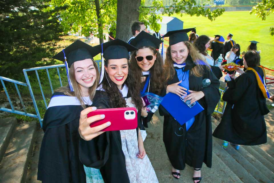Group of female graduates pose for a selfie.