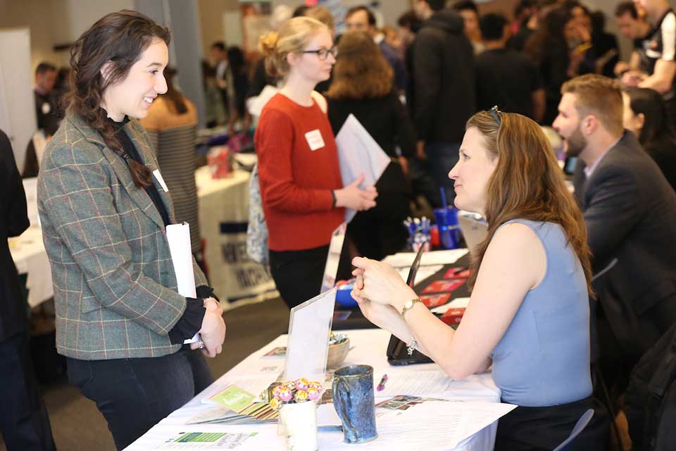 Student or young alum speaks to employer at at table at a Hiatt Event