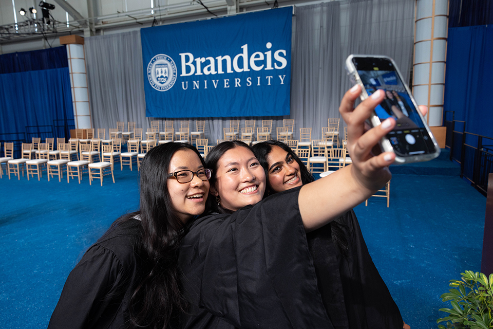 Students take a selfie together in caps and gowns.