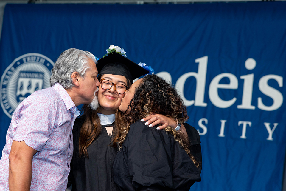 Zoraida Ibarra in grad cap and gown hugging and kissing parents