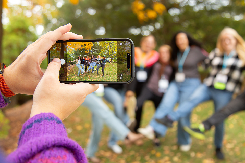 hands taking a photo on a phone of a group of alumni 