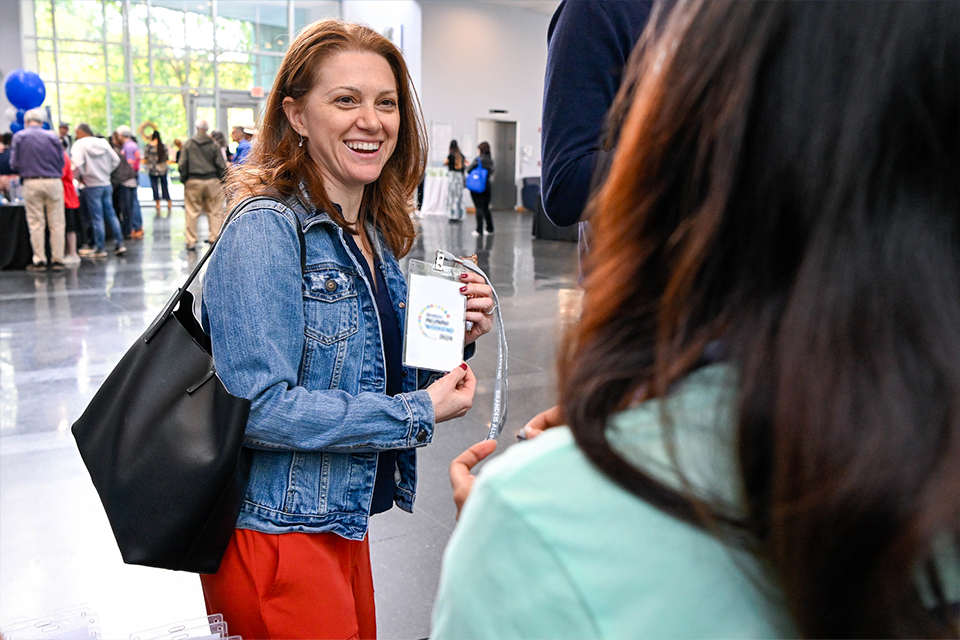 alumna smiling holding her registration badge