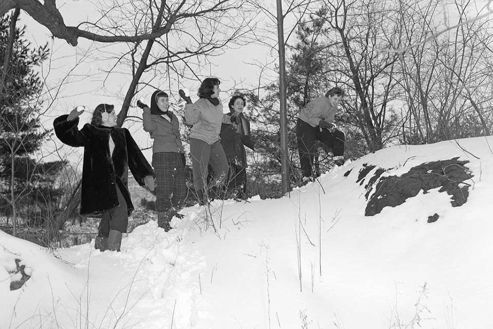 Ladies from the Class of 1952 have a snowball fight on campus.