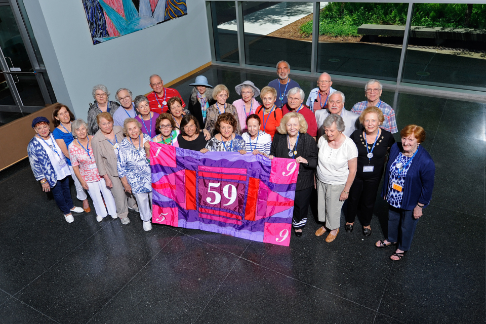 group of alumni from class of 1959 holding color flag