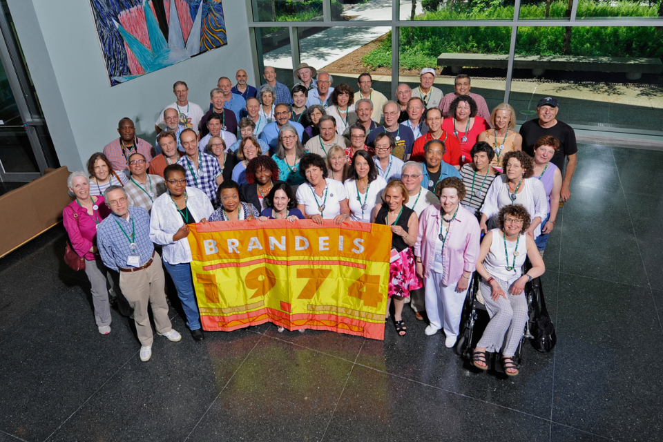 group of alumni from class of 1974 holding colorful class flag