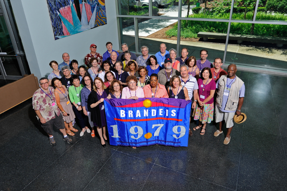 group of alumni from the class of 1979 gathered together holding their class flag