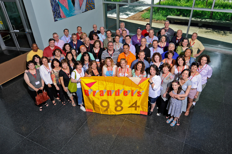 group of alumni from 1984 gathered holding class flag