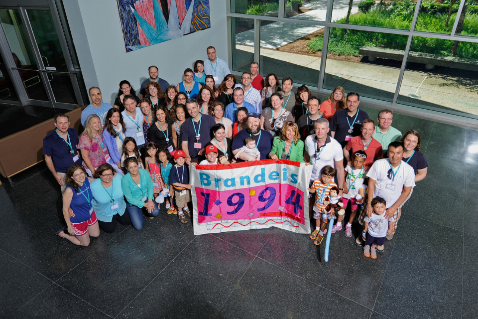 group of 1994 alumni gathered holding class flag