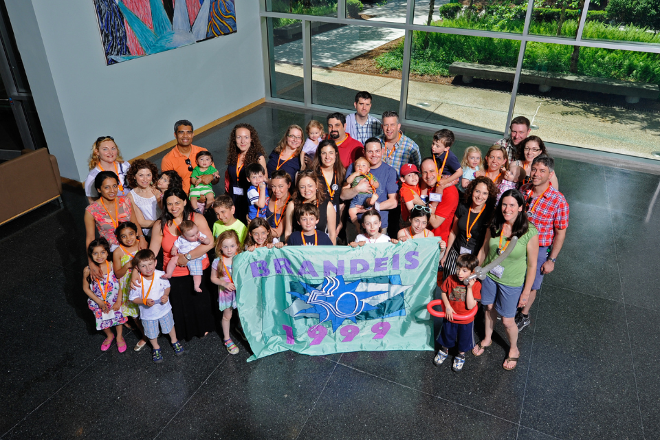 group of 1999 alumni gathered holding their class flag