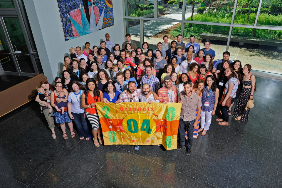 group of 2004 alumni gathered holding class flag