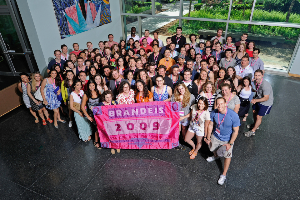 group of 2009 alums gathered holding class flag