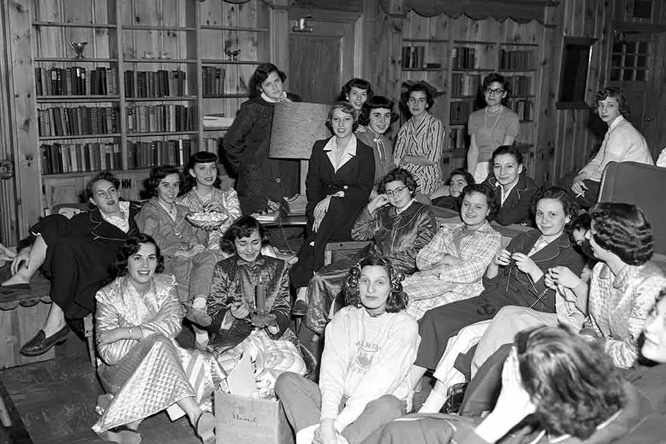 Group of female students in pajamas in a common room.