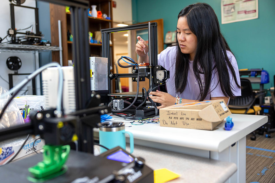 Female student working on a piece of technology in the Makerlab