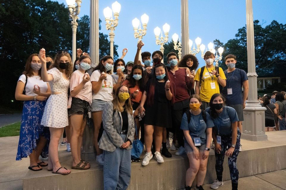 Students wearing masks standing next to the Light of Reason sculpture
