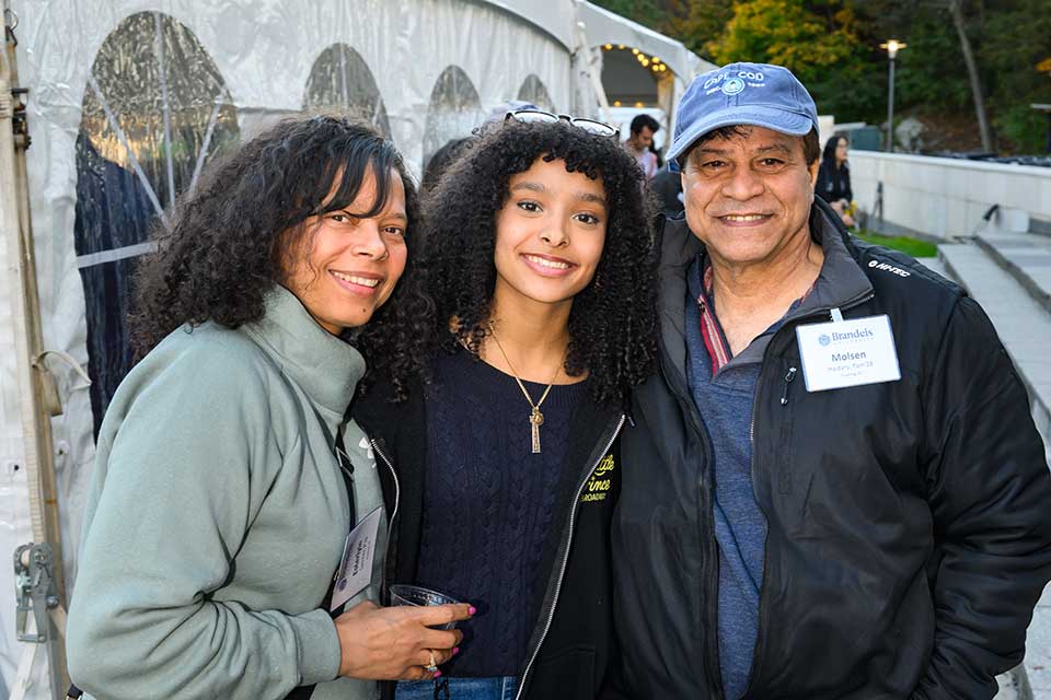 Two parents with their daughter, a student, in the center. 