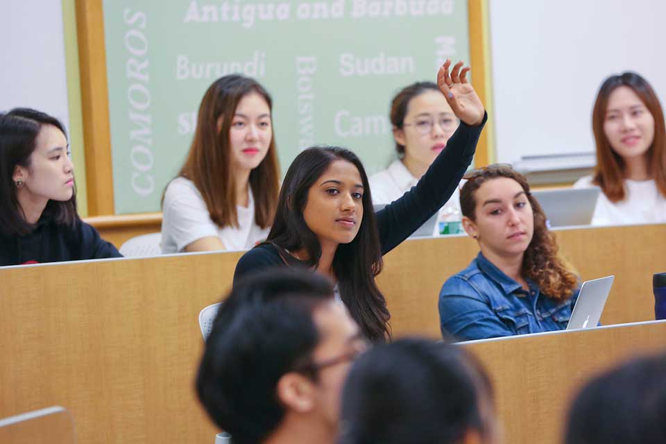 Female student raises hand in class at the International Business School. 