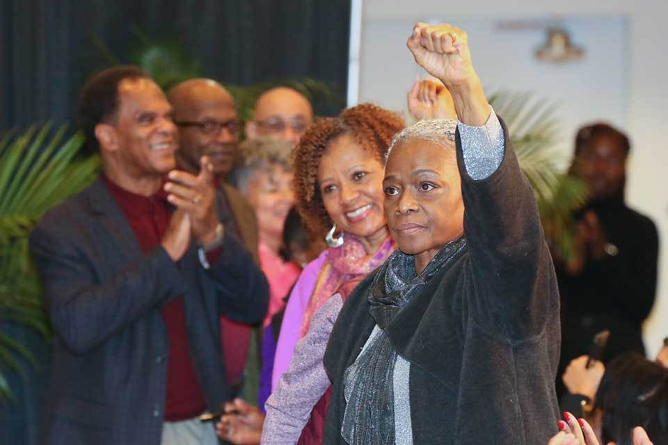 Black woman raises left fist at AAAS commemoration ceremony