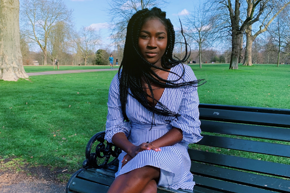 Student Elizabeth Dabanka sits on a bench in front of a green landscape