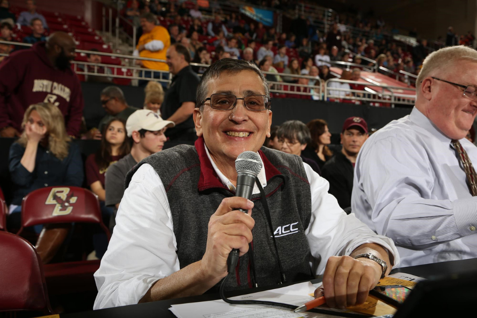 Andy Jick wearing sunglasses and holding a microphone at a sporting event