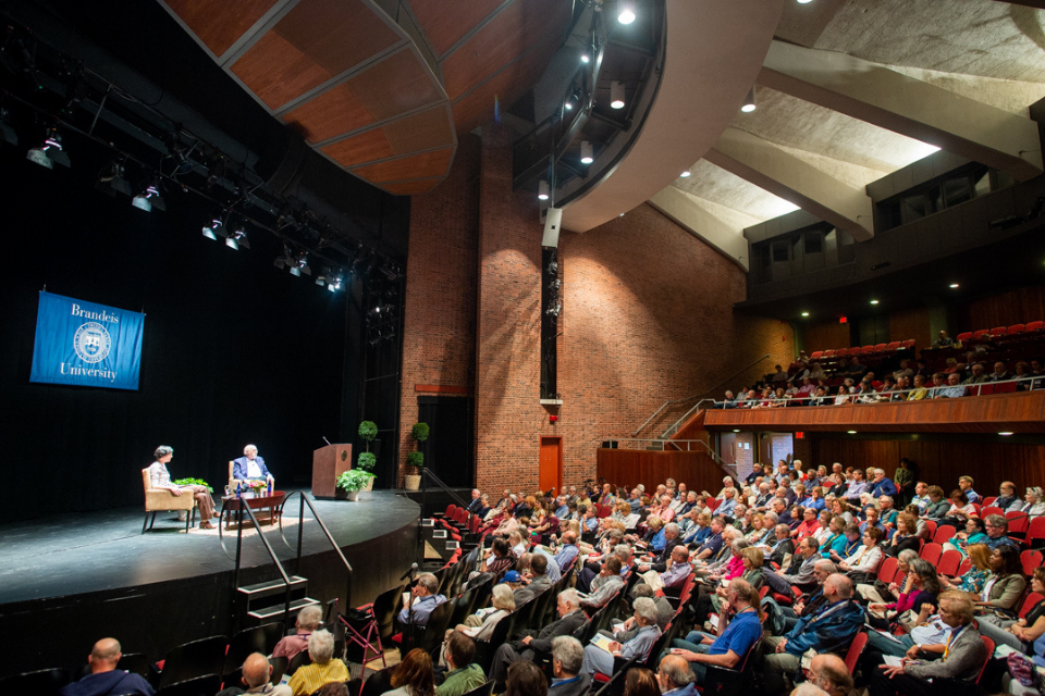 Professor Maura Jane Farrelly and Walt Mossbery sit on a stage in front of a full audience to discuss media literacy during the Alumni College 2019 event