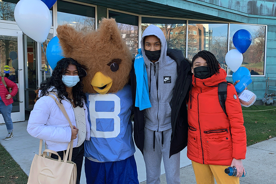 Students with masks pose with mascot Ollie the Owl. 