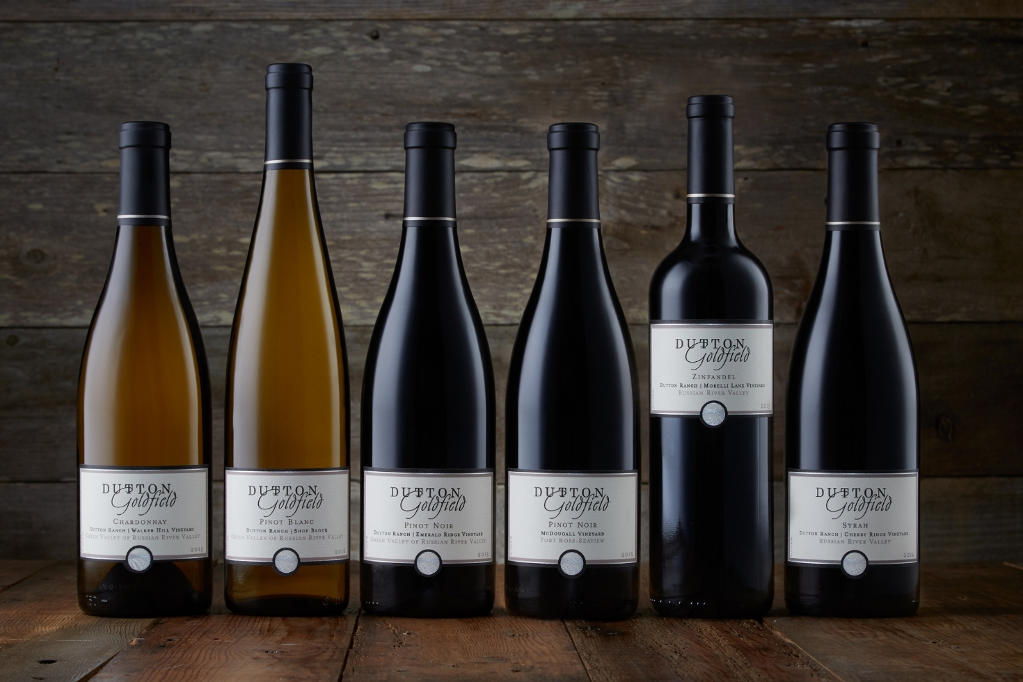 Six bottles of wine in front of a wooden wall