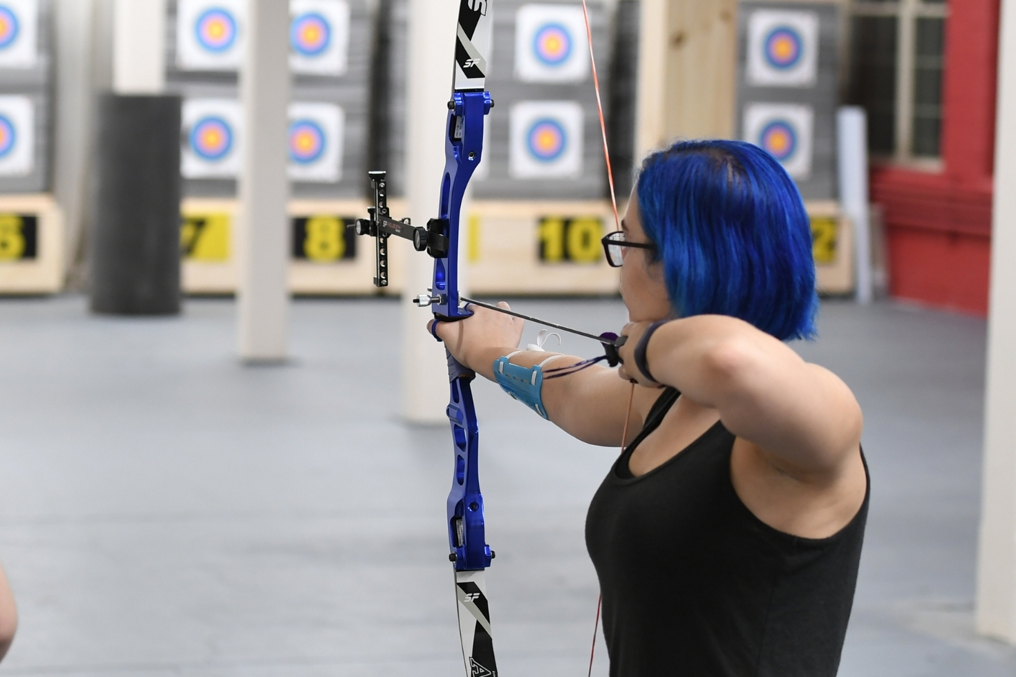 Woman with blue hair holding a bow and arrow