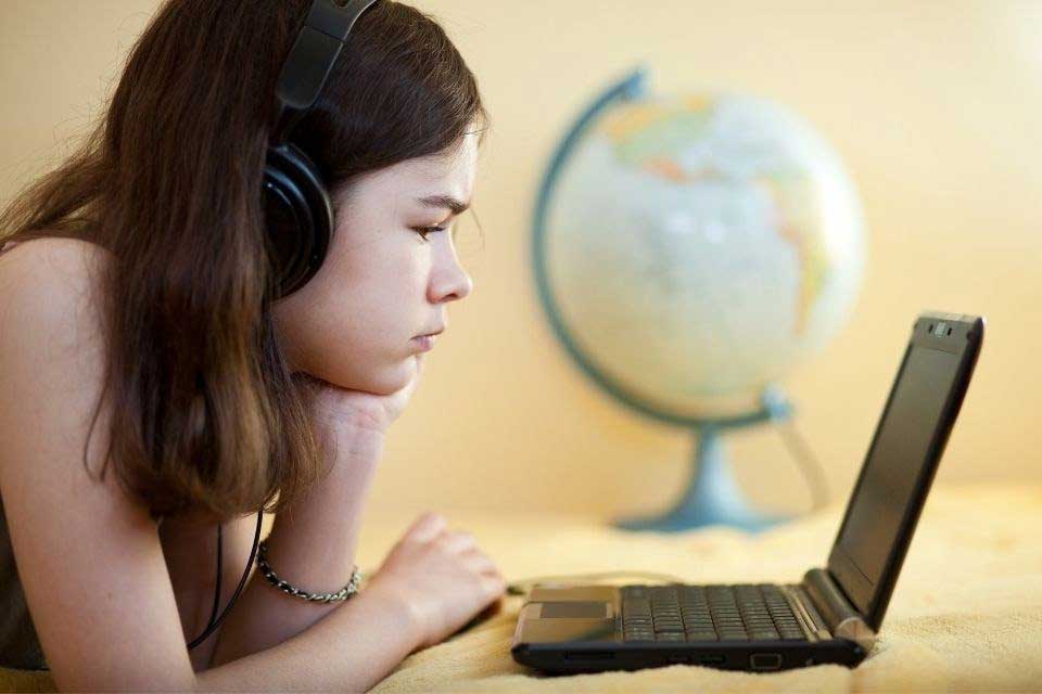 School-aged girl wearing headphones and staring at laptop