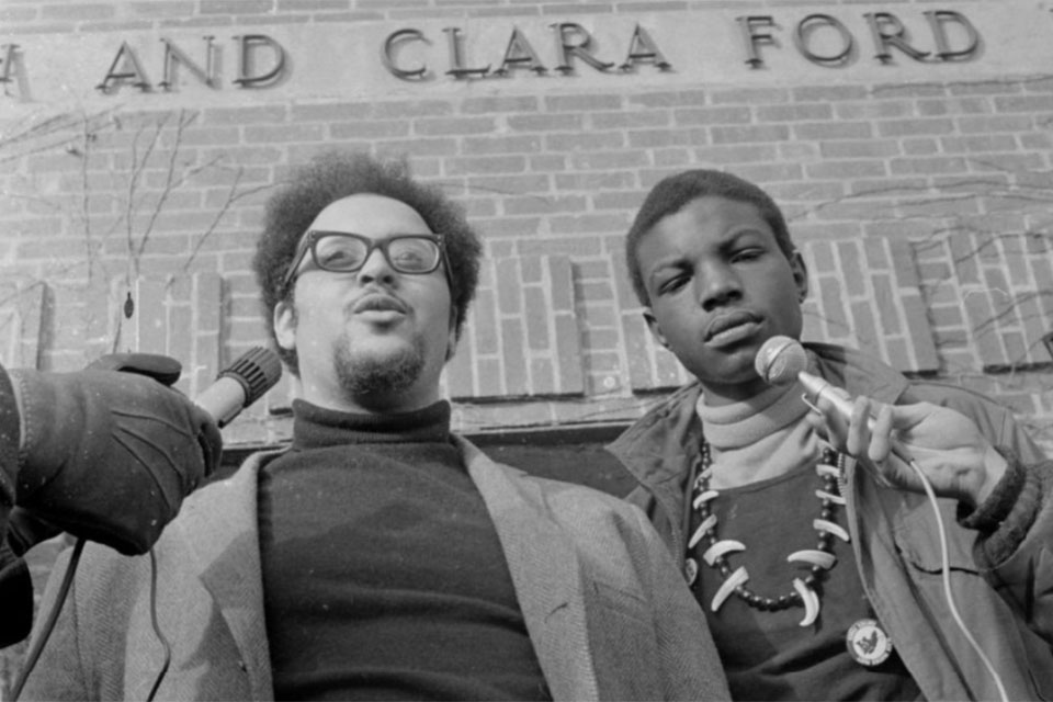 Black and white image of Reggie Sapp with  Randall Bailey outside of Ford Hall in 1969