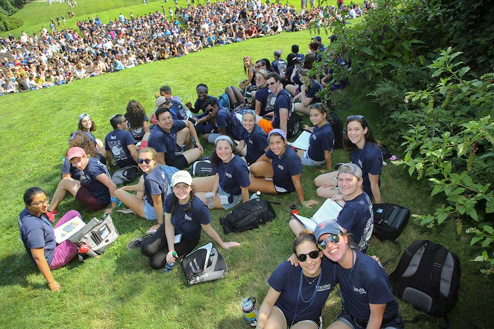 Large group of Brandeis students sitting on the lawn at orientation.