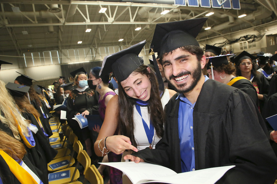 Students find their names in the commencement program.