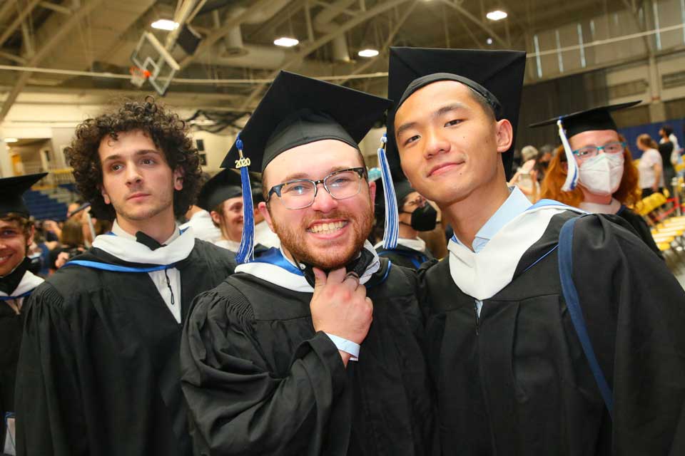 Two male graduates smiling in a crowd at Recommencement