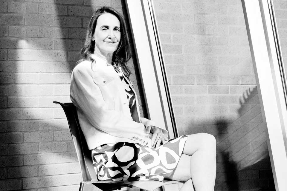 Bonnie Berger smiling and seated, next to a window. 