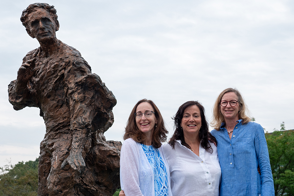 Louisa Brandeis Popkin, Anne Brandeis Popkin, and Susan Brandeis Cahn stand in front of a statue of their great-grandfather, Louis Brandeis, on Brandeis University’s campus.