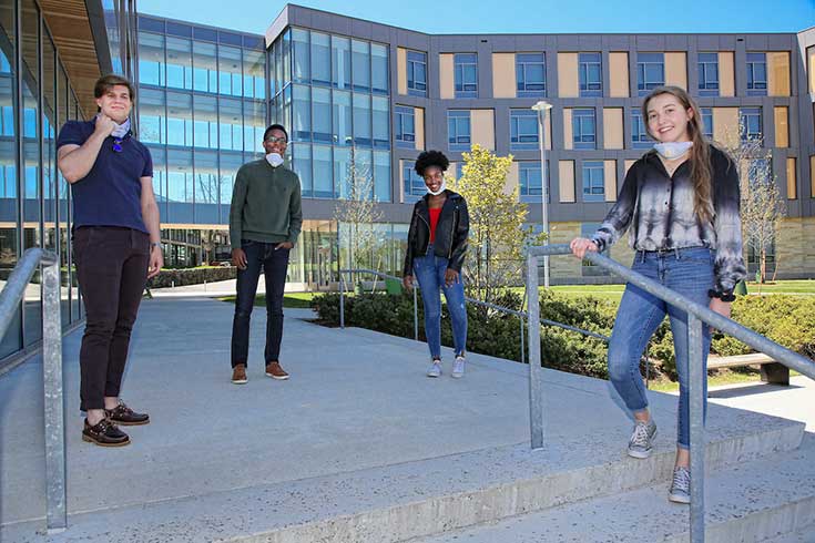 Four students standing in front of skyline residence hall