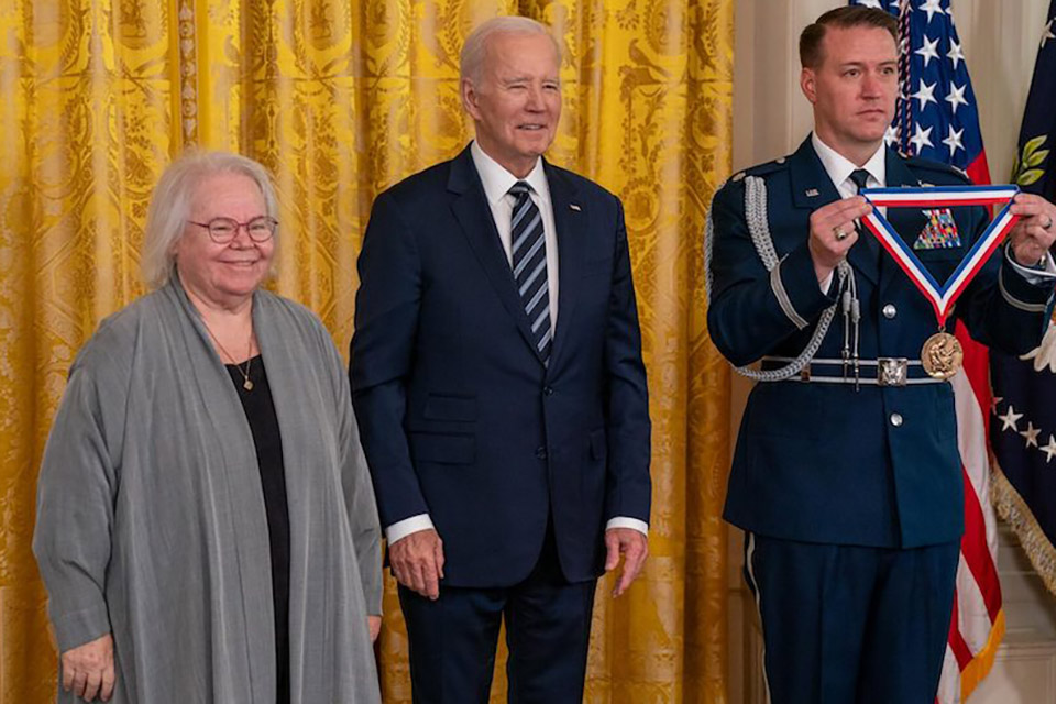 Professor Eve Marder with President Joe Biden and a military officer holding a medal