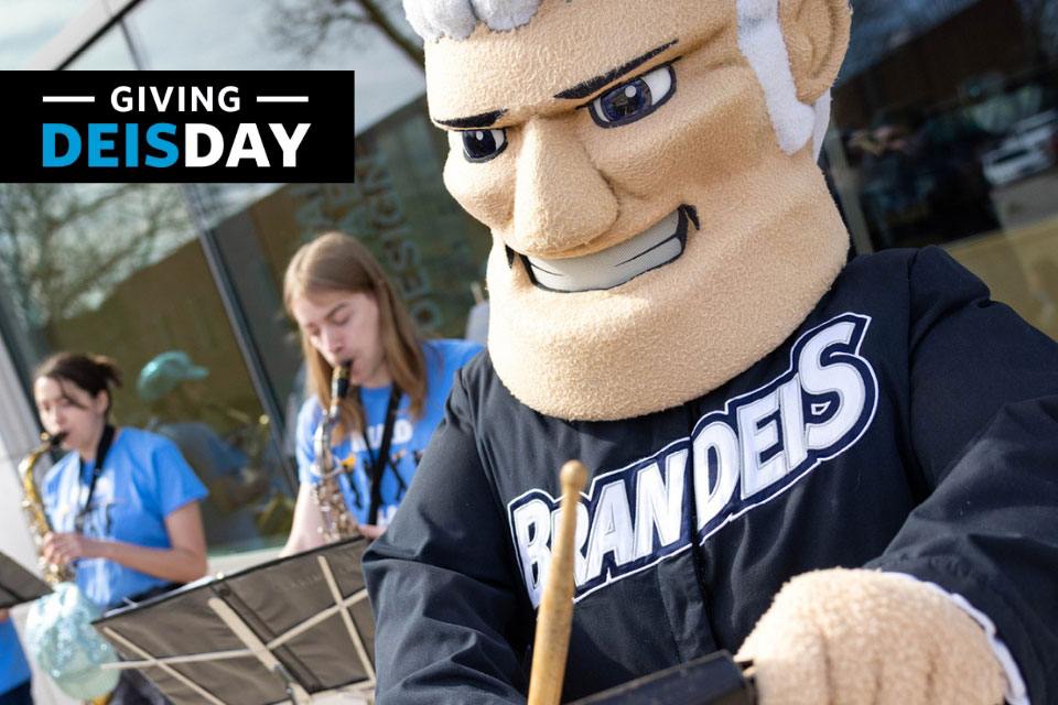The Judge mascot beats a drum in front of a student band. Text reads: "Giving DEISday."