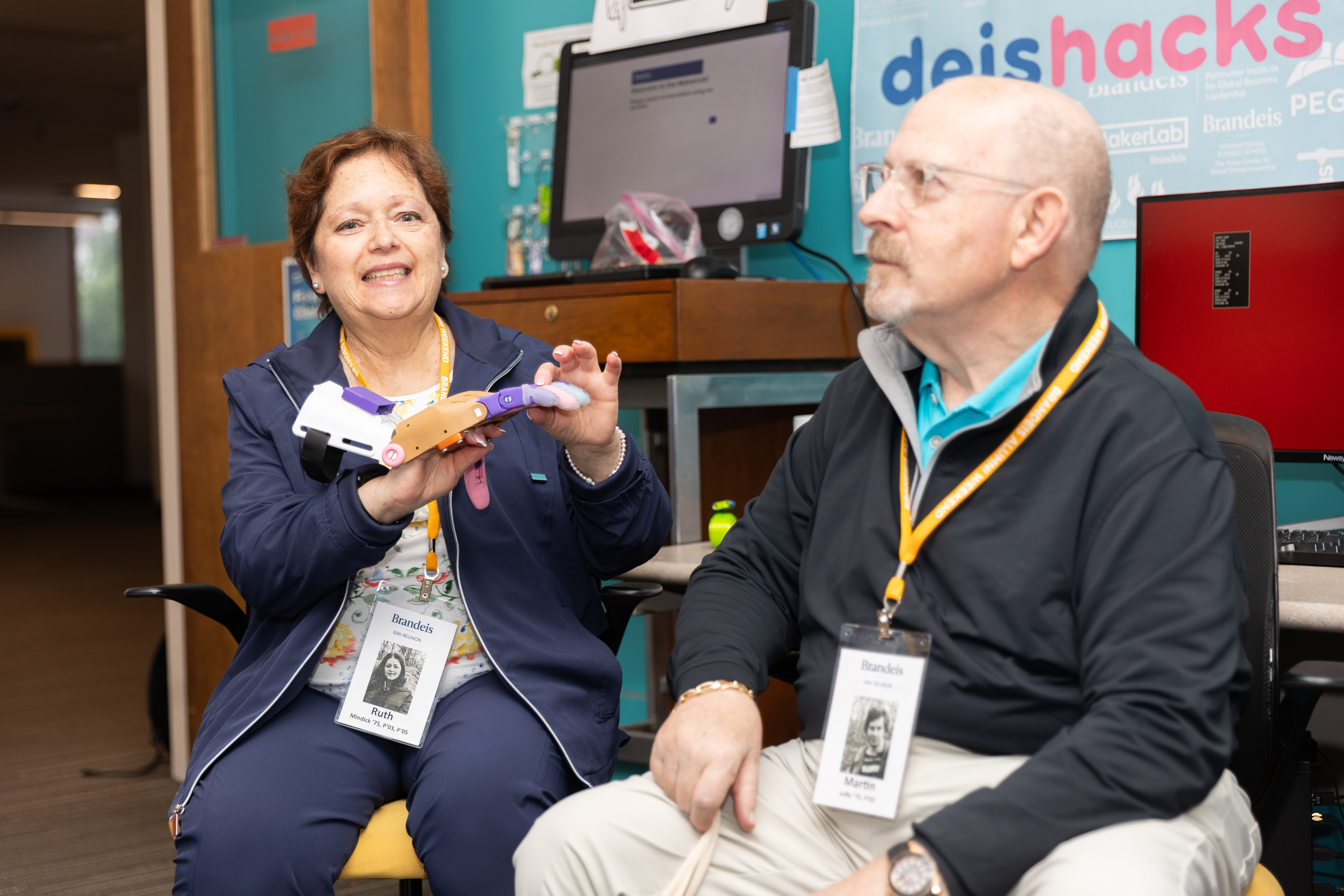 Woman holding a robotic hand siting next to a man