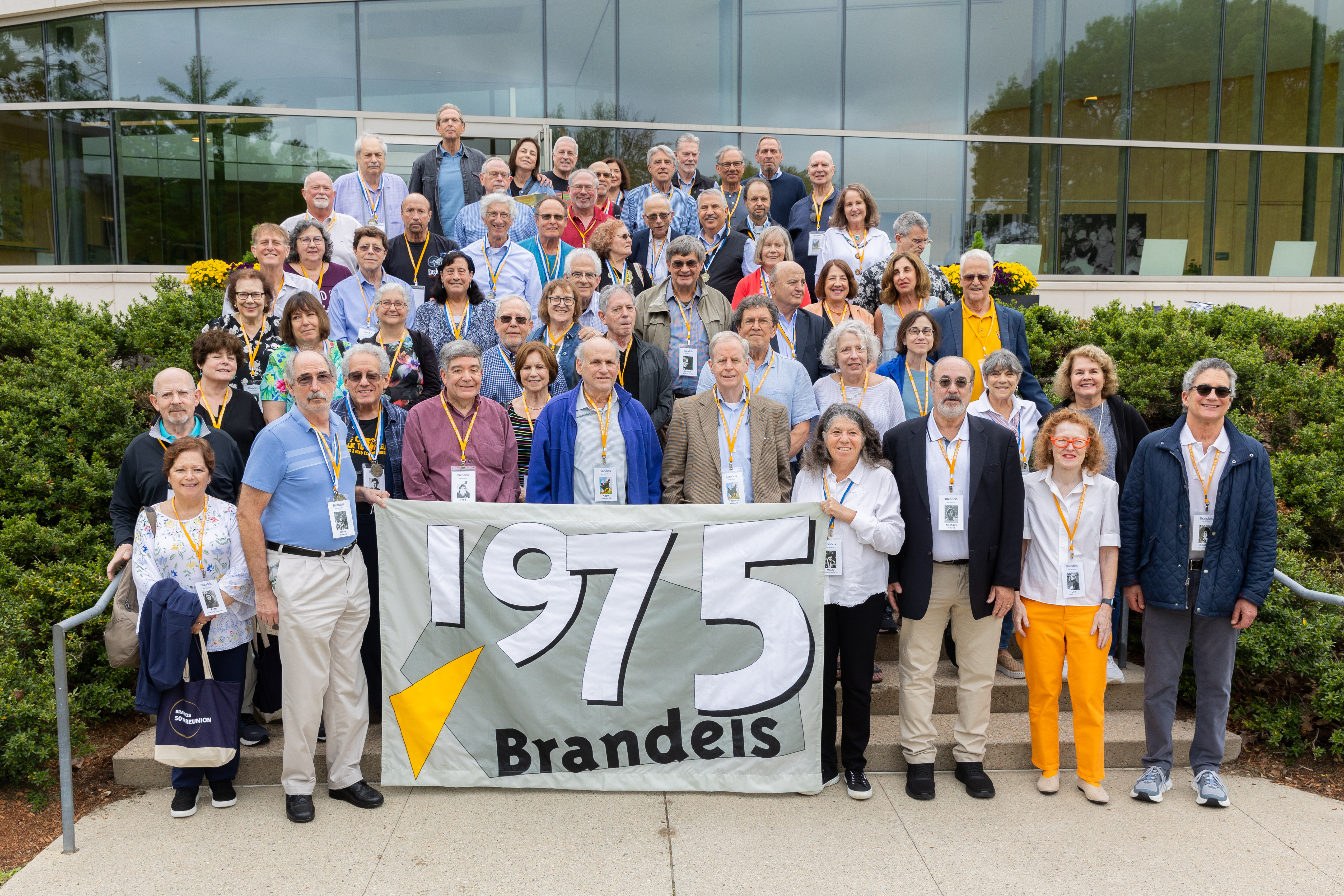 Group photo of people standing on stairs holding the Class of 1975 flag
