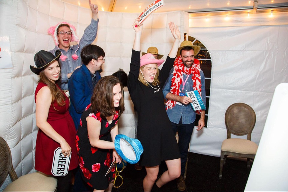 Six people in costumes laugh during a college event