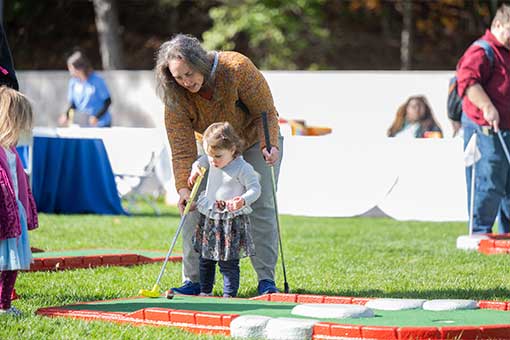 A parent helps a child play mini golf