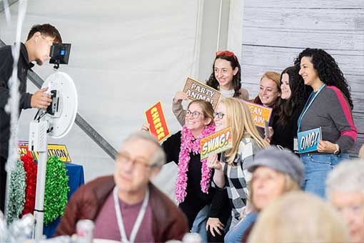 Alumni hold signs and pose for a photo booth picture