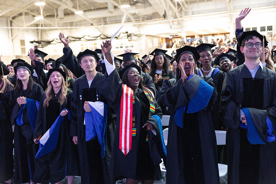 Graduate students cheer and celebrate at the graduate commencement ceremony.