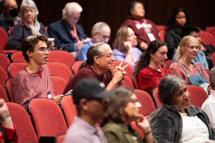 Man smiling sitting in an audience hall