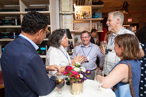 Men and women talking around a table at a cocktail event.