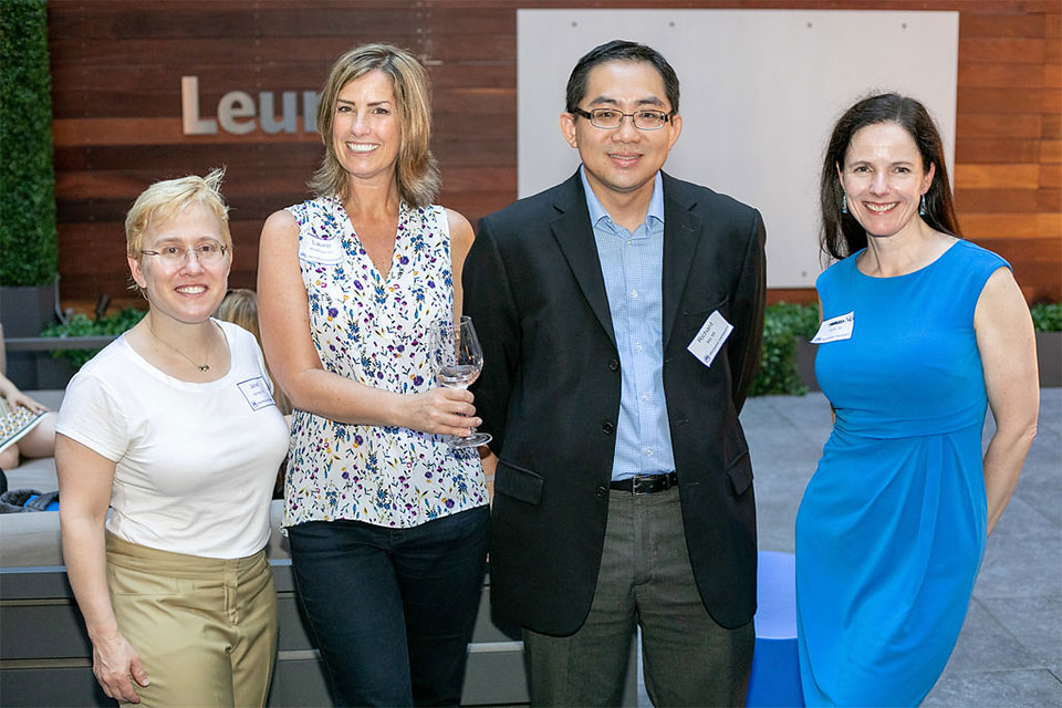 four alumni arm in arm on rooftop deck