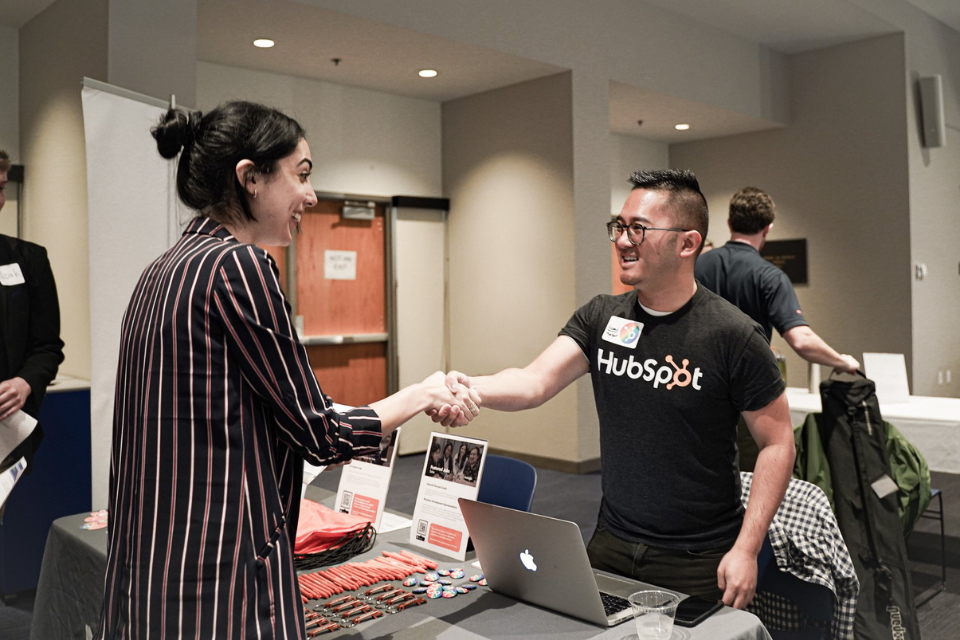 Recruiter wearing a Hubspot shirt shakes applicant's hand at career fair