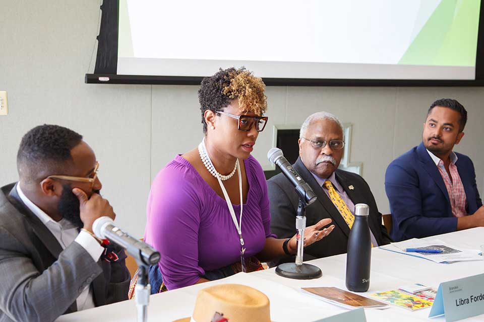 Alumni panelists sit at table with microphones